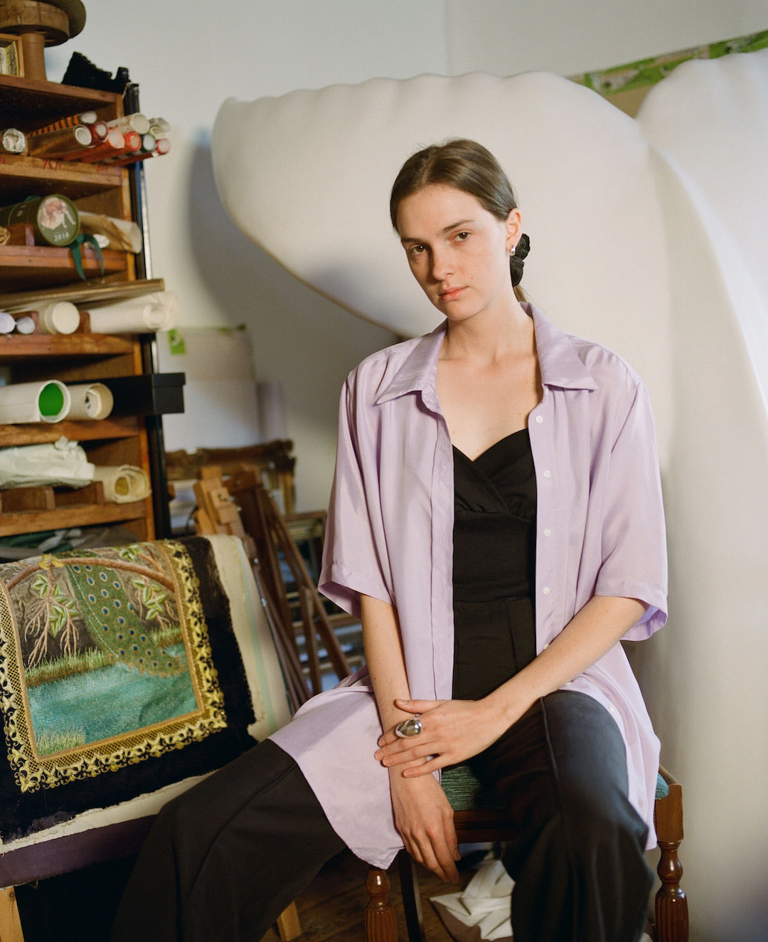 A woman sitting on a chair in a purple OVNA OVICH Eleanor Pant – Onyx shirt.