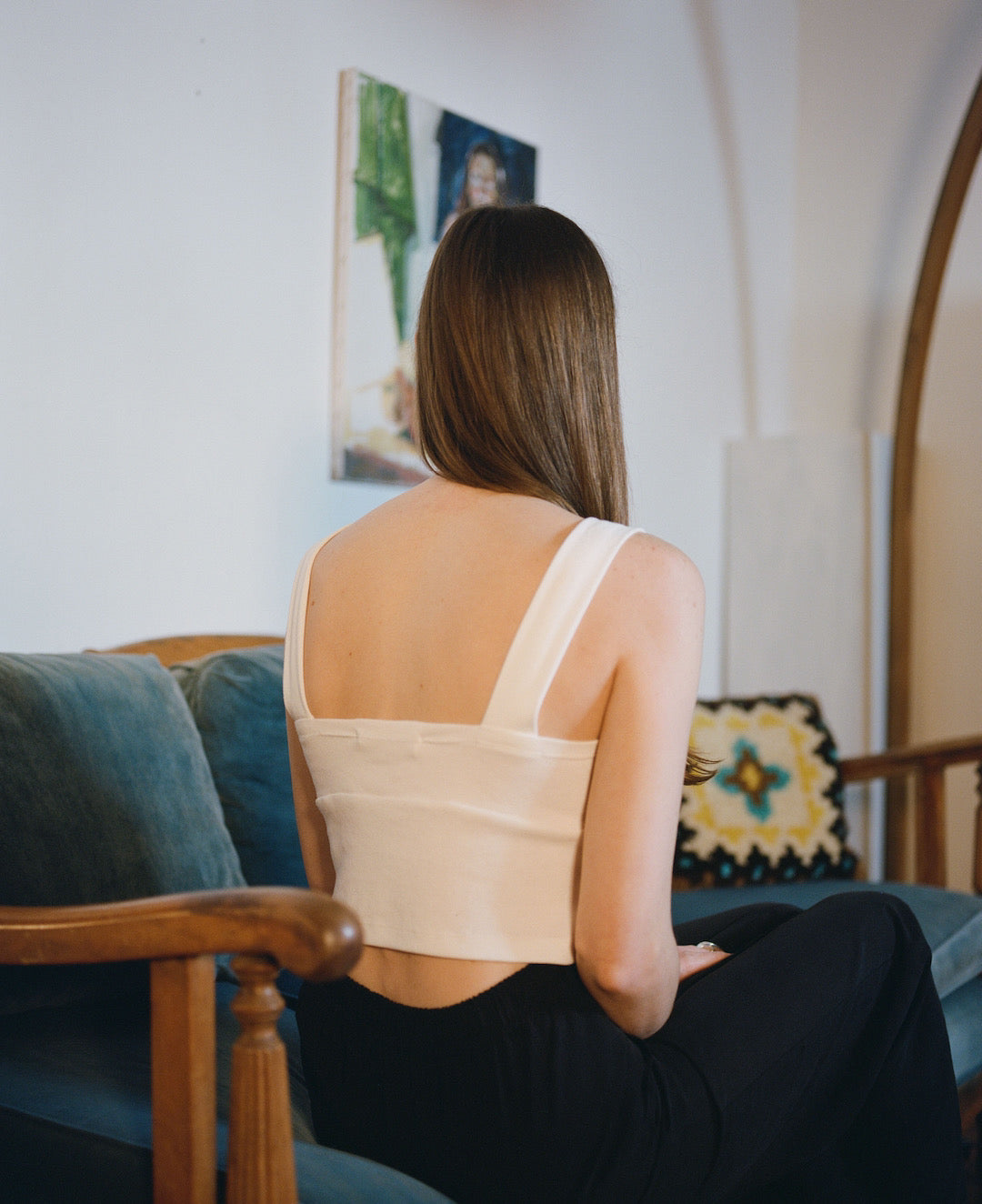 The back of a woman sitting on a couch, wearing the Eleanor Pant in Onyx by OVNA OVICH.