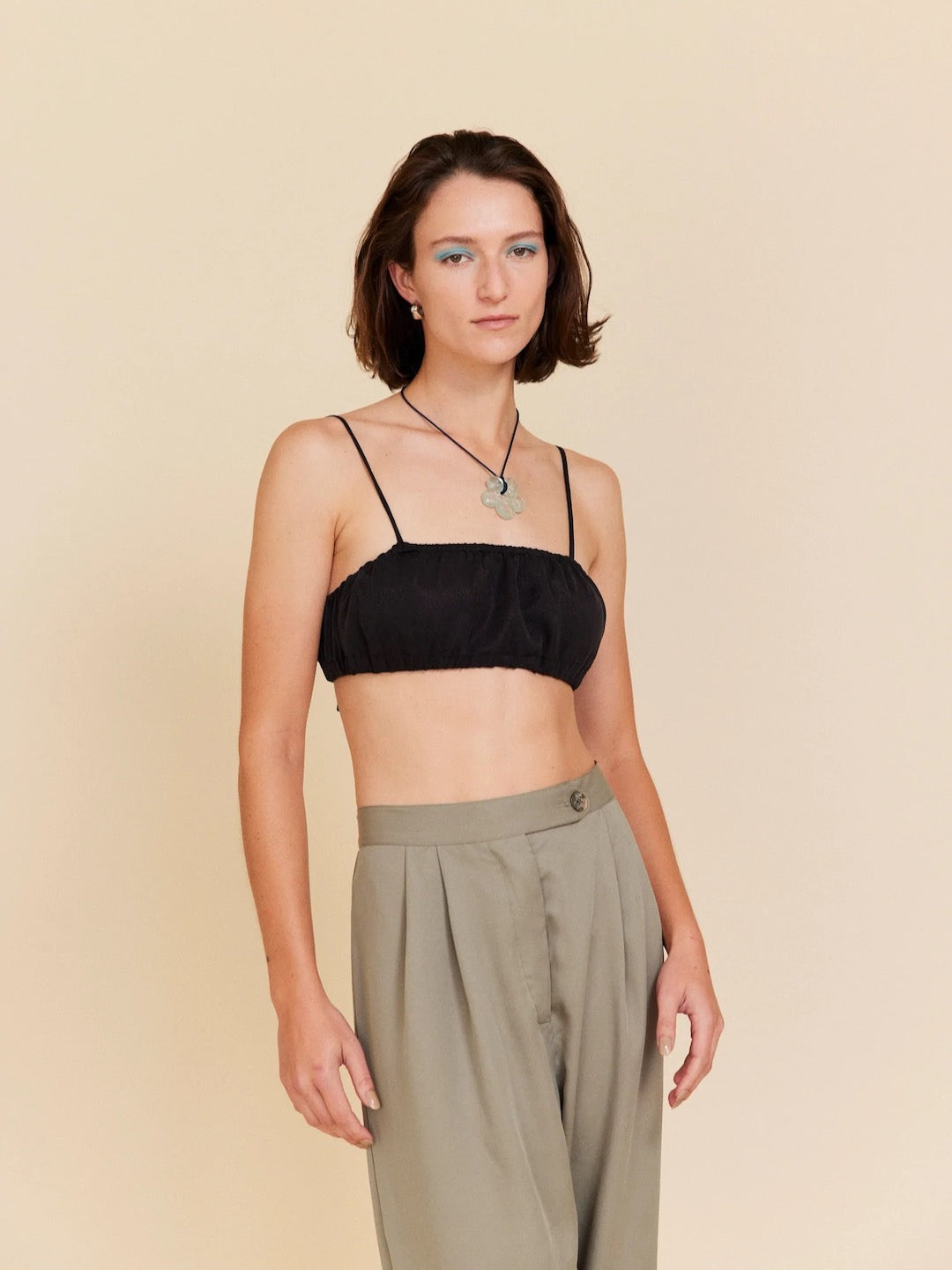 A woman wearing a black Little Joy Bralette – Onyx by OVNA OVICH and khaki pants.