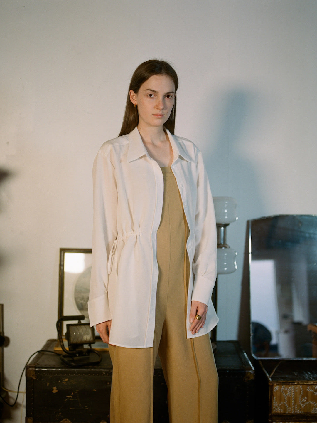 A woman in an OVNA OVICH tan jumpsuit standing in front of a mirror.
