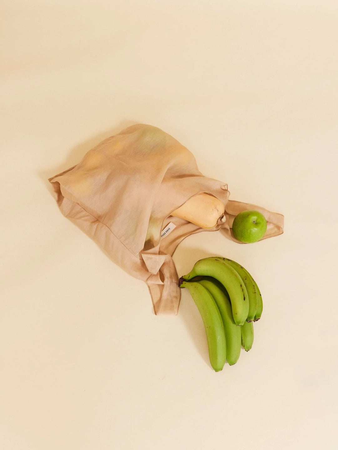 A Wander Bag - Champagne by OVNA OVICH with bananas and apples.