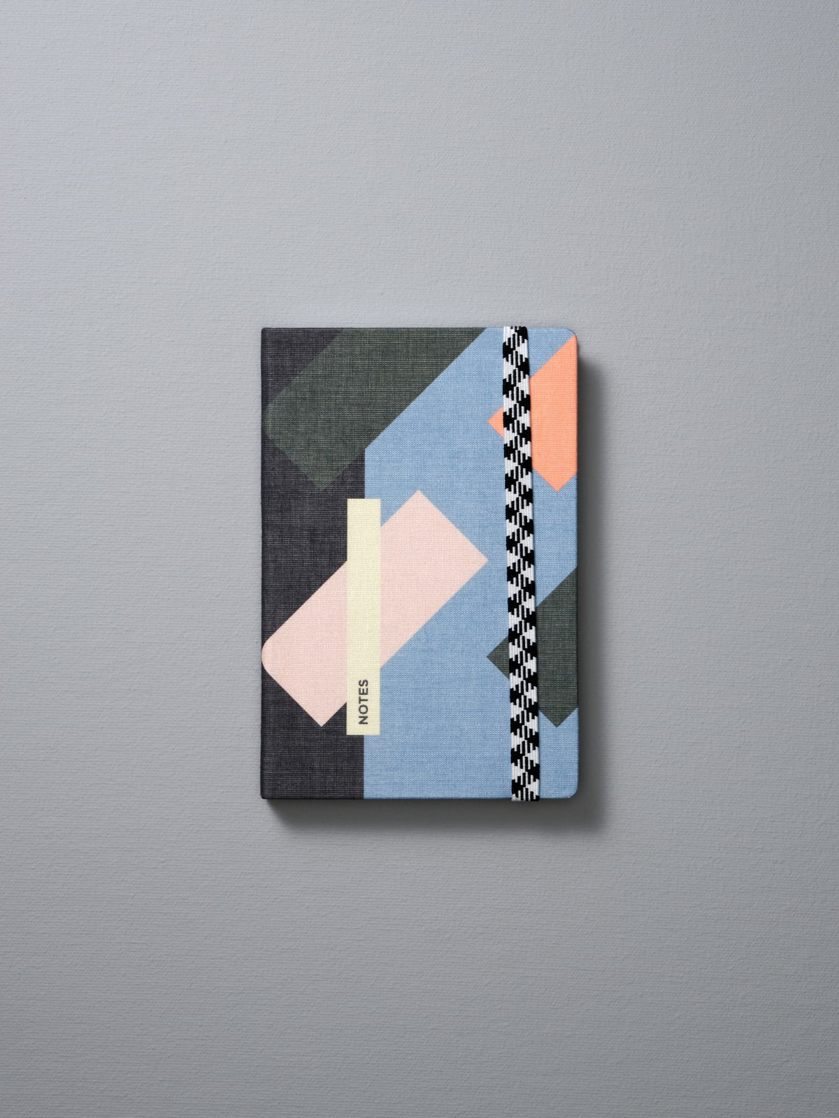 A Papier Tigre A6 Canvas Notebook – Dot Grid with geometric shapes on a grey background.