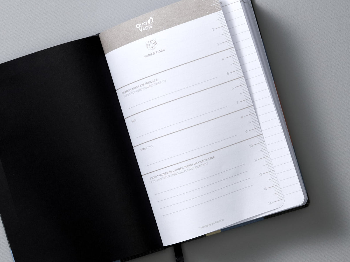 An A6 Canvas Notebook - Dot Grid by Papier Tigre is open on a gray surface.