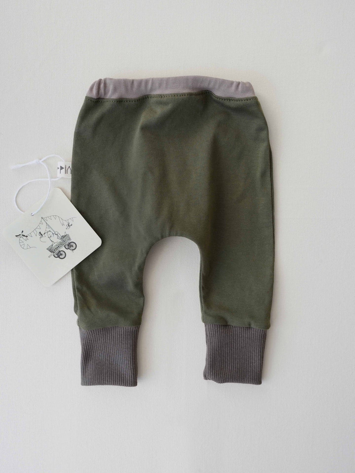 A Peppin Baby Gift Box – Forest&#39;s green pants with a tag on them.
