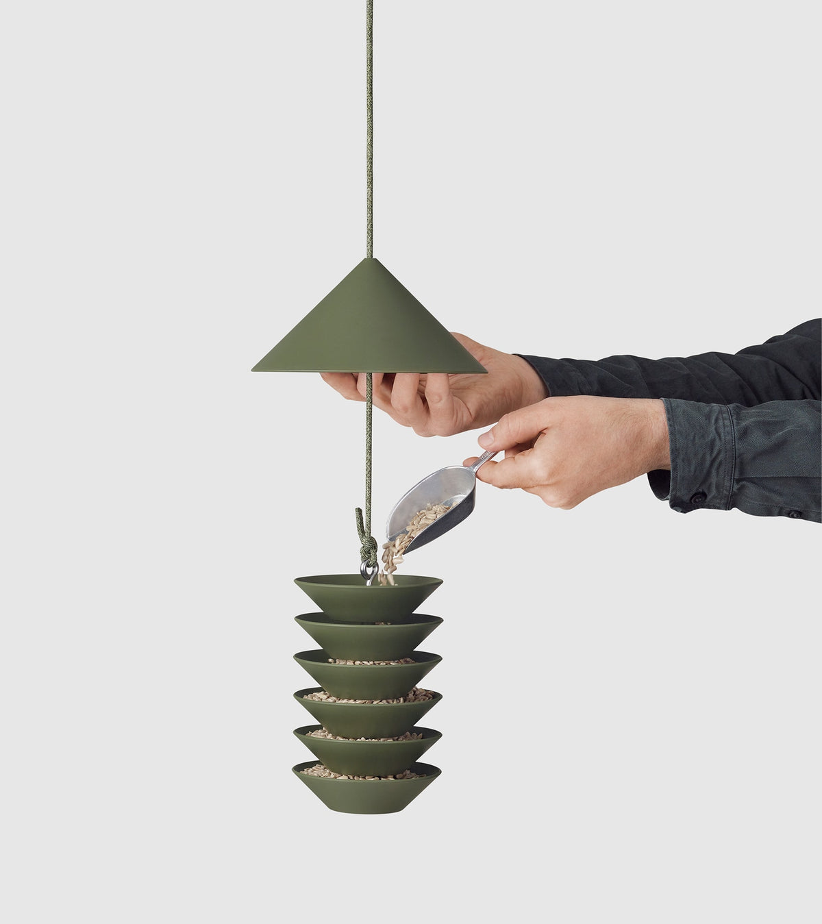 A person holding a Bird Silo – Slate bird feeder in an olive green color from Pidät.