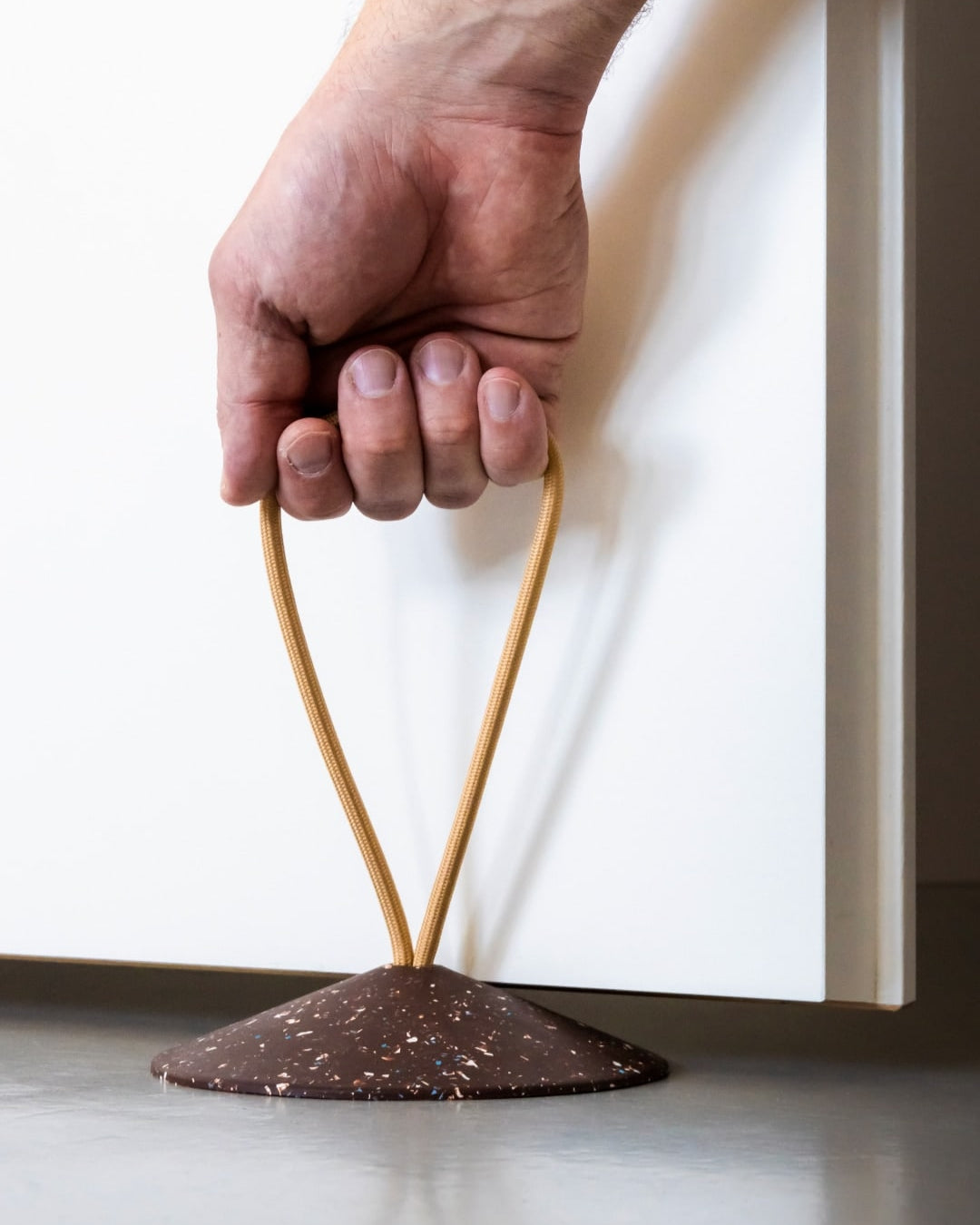 A hand is holding a piece of chocolate on a Pidät - STOP Doorstop.