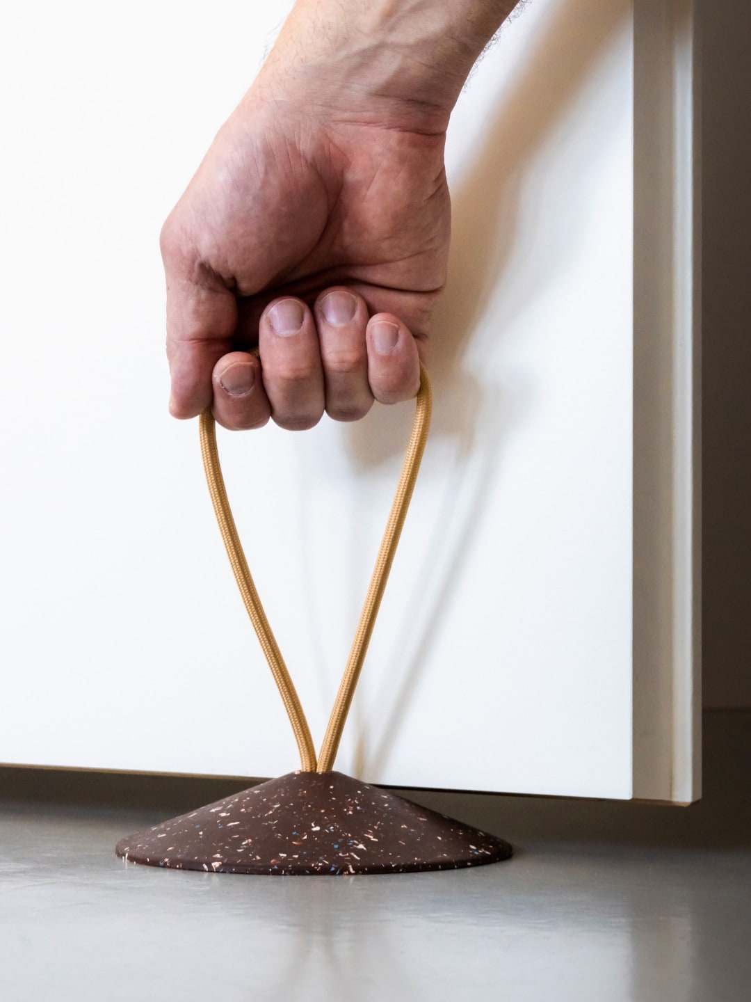 A hand is holding a piece of chocolate on a Pidät - STOP Doorstop.