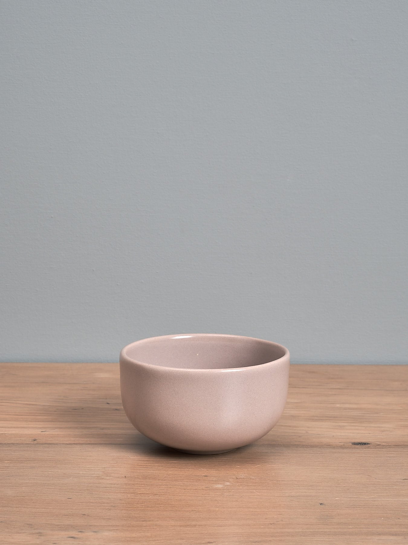 An Olive Bowl - Dusty Pink by Gidon Bing sitting on top of a wooden table.