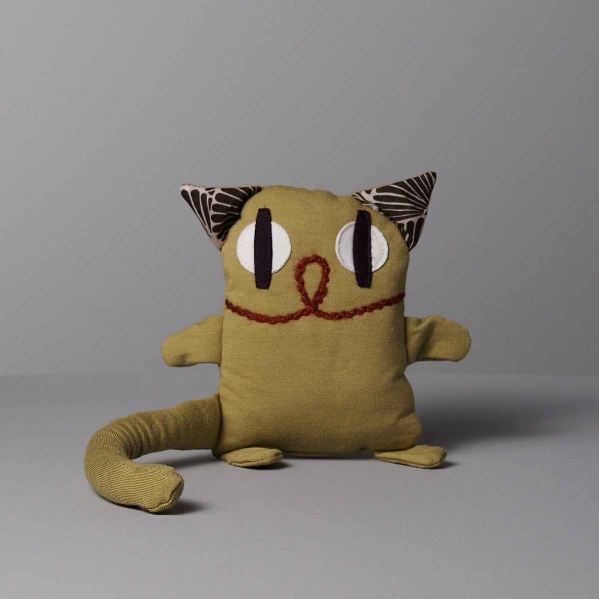 A yellow Serge the Cat stuffed animal on a grey background by Raplapla.