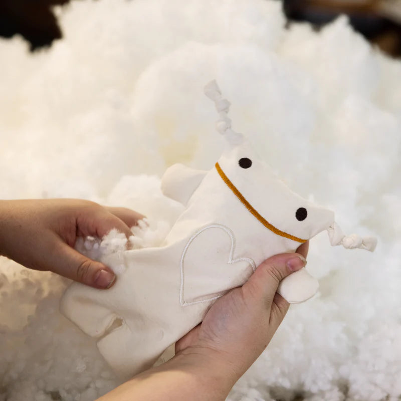 A child is holding a Monsieur Tsé-Tsé Classic stuffed animal by Raplapla on top of a pile of snow.