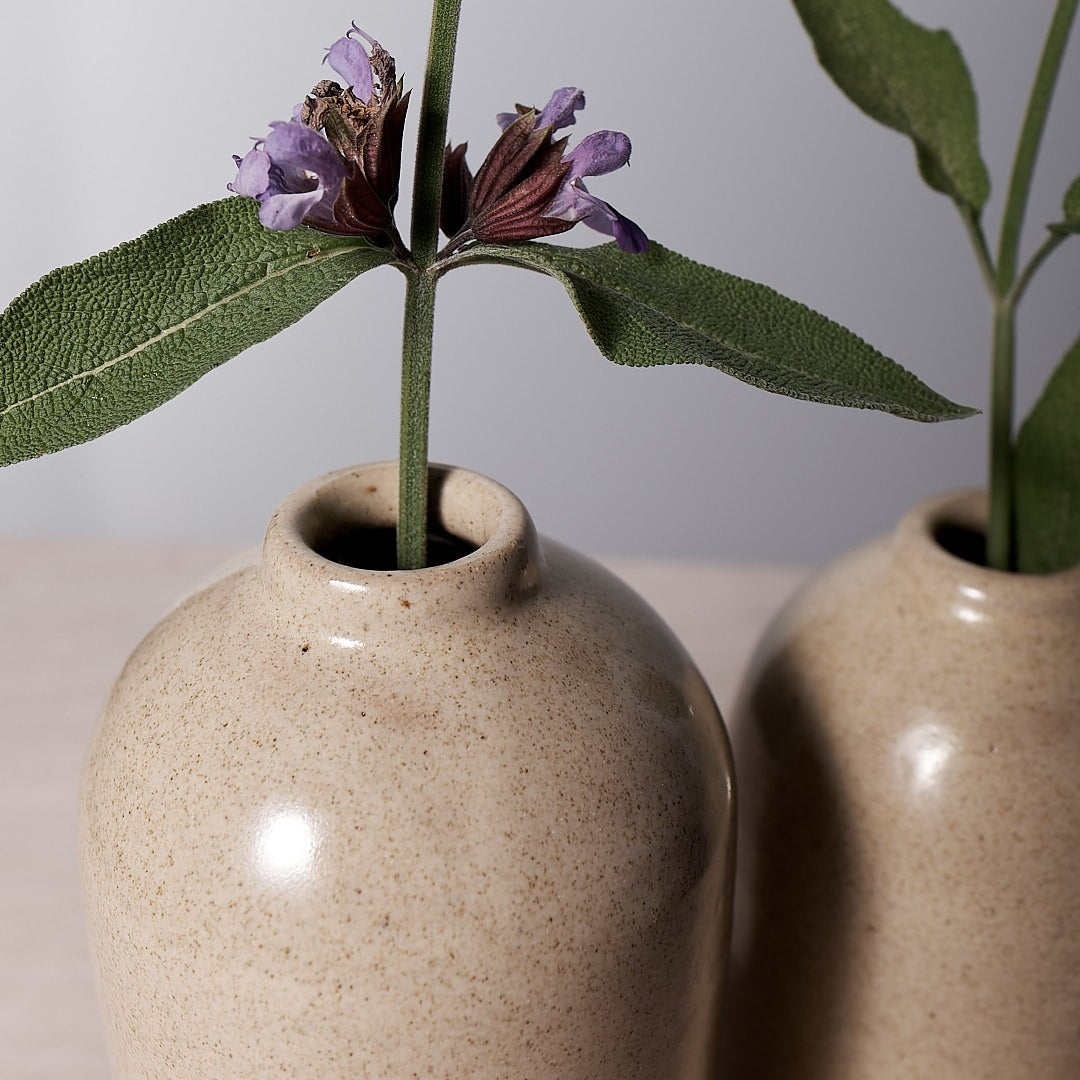 Two Richard Beauchamp small bud vases, named Sand, with purple flowers in them, handmade.