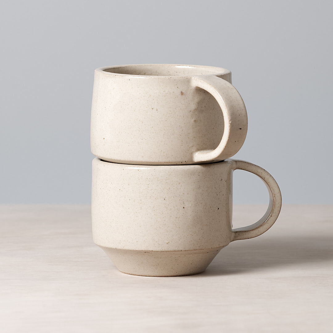 A beautifully handmade Richard Beauchamp C-handled Stacking Mug – Beige with a beige coloured glaze, featuring two mugs stacked on top of each other.