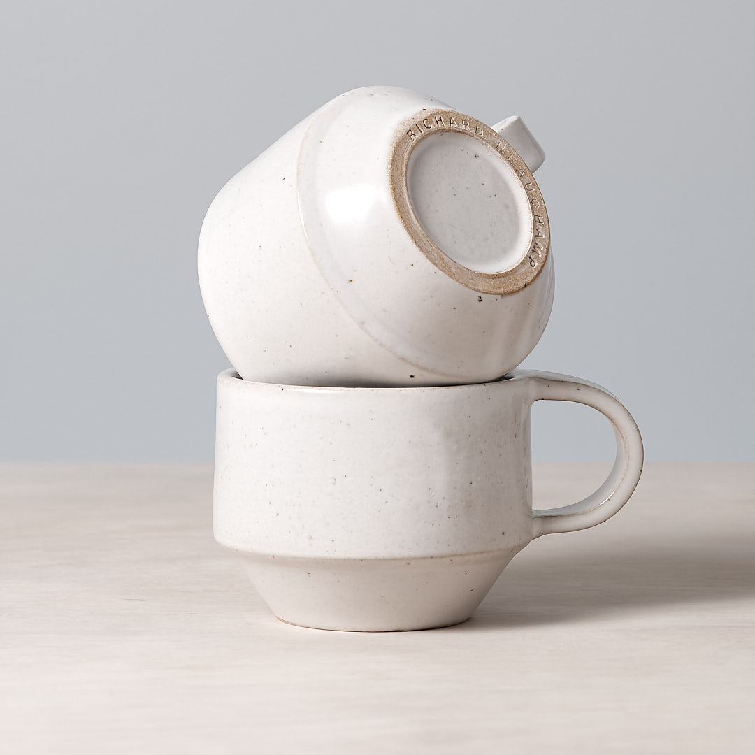 Two Richard Beauchamp C-handled Stacking Mugs - White stacked on top of each other.