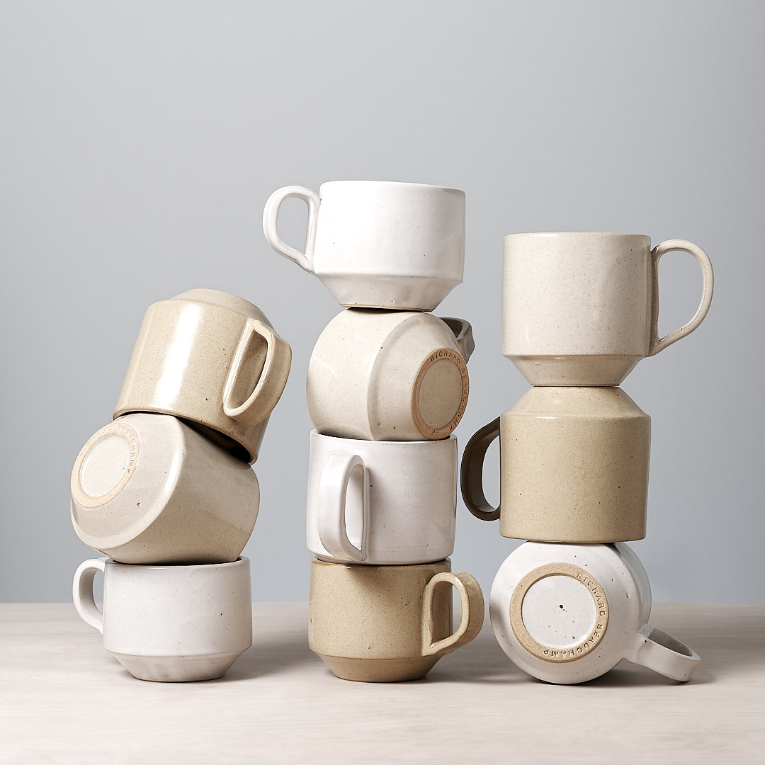 A stack of Richard Beauchamp Medium Stacking Mugs - Sand on a table.