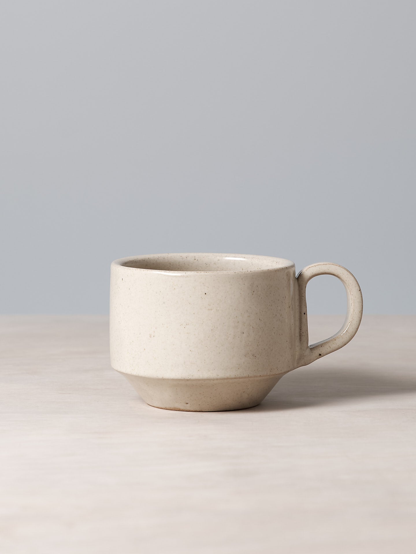 A Medium Stacking Mug – Beige from Richard Beauchamp sitting on top of a table.
