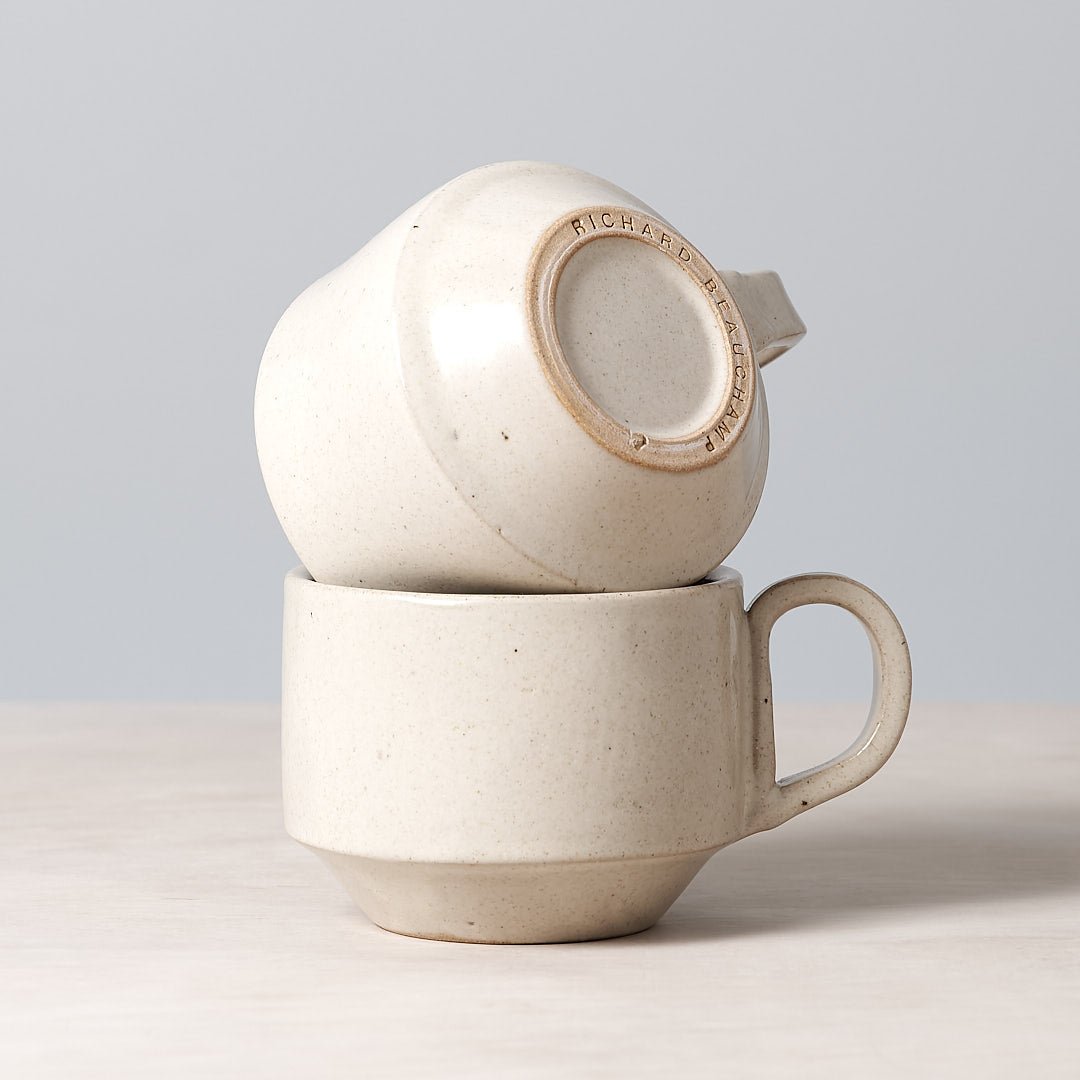 Two Richard Beauchamp Medium Stacking Mugs - Beige stacked on top of each other.