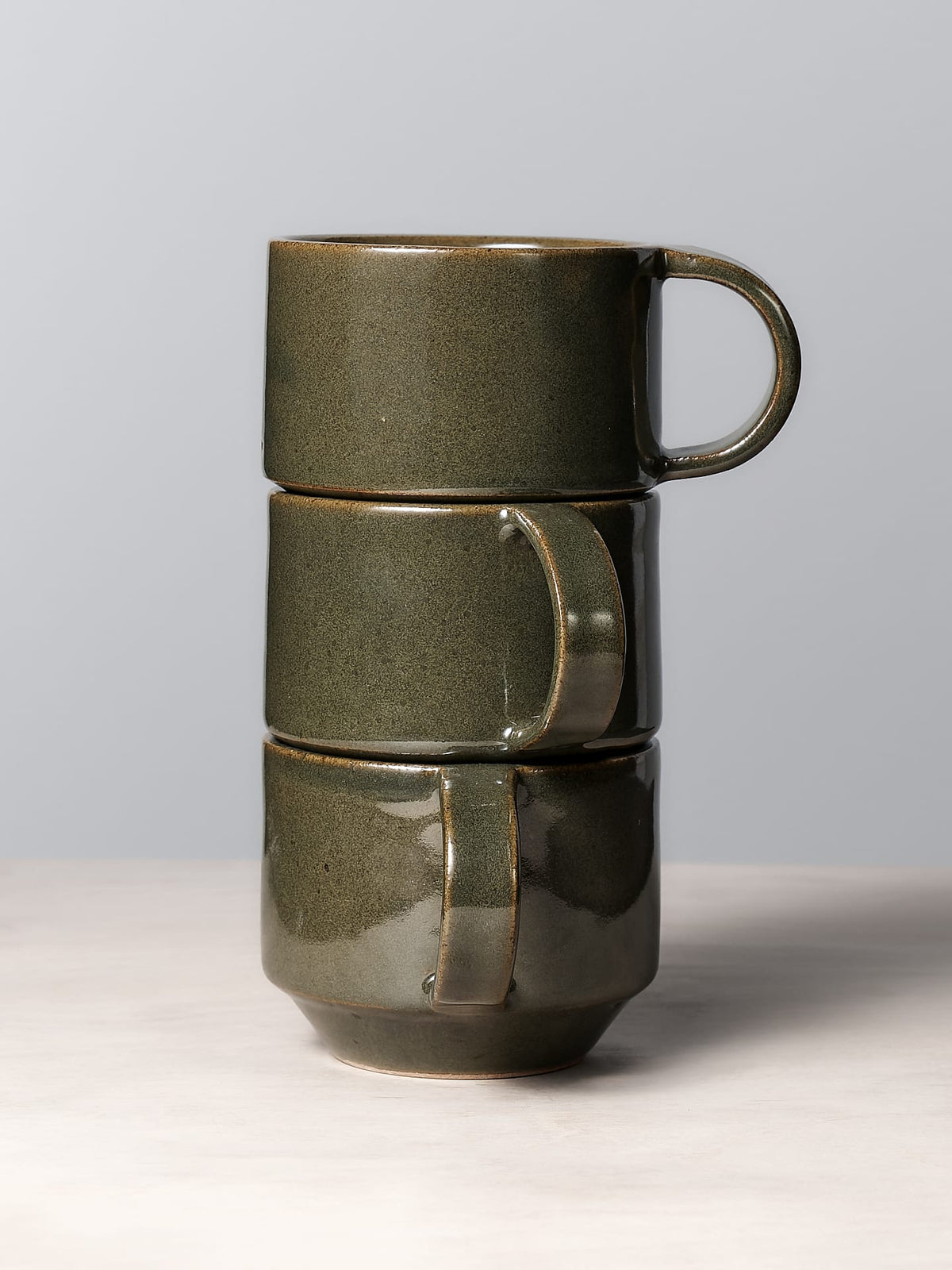Three Richard Beauchamp C-handled Stacking Mugs - Green stacked on top of each other.