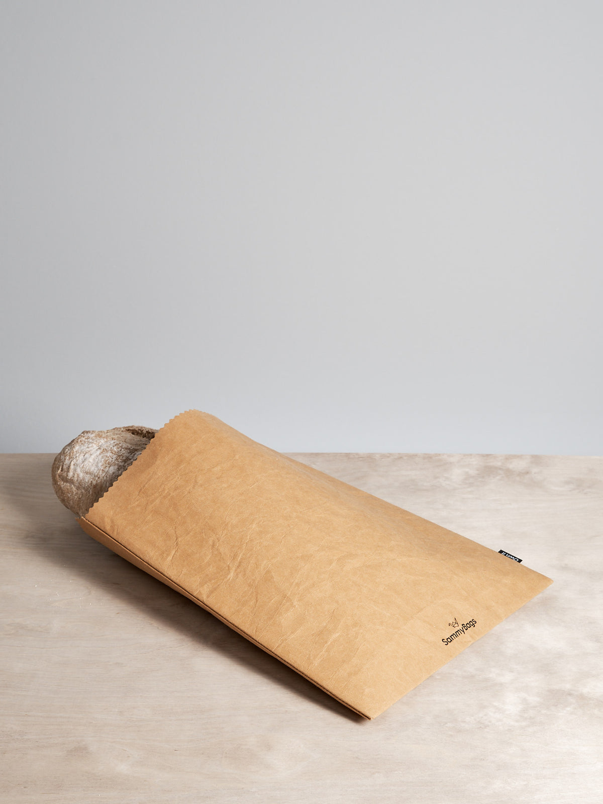 A Sammy Bags branded Reusable Flat Bag - XL sitting on top of a wooden table.