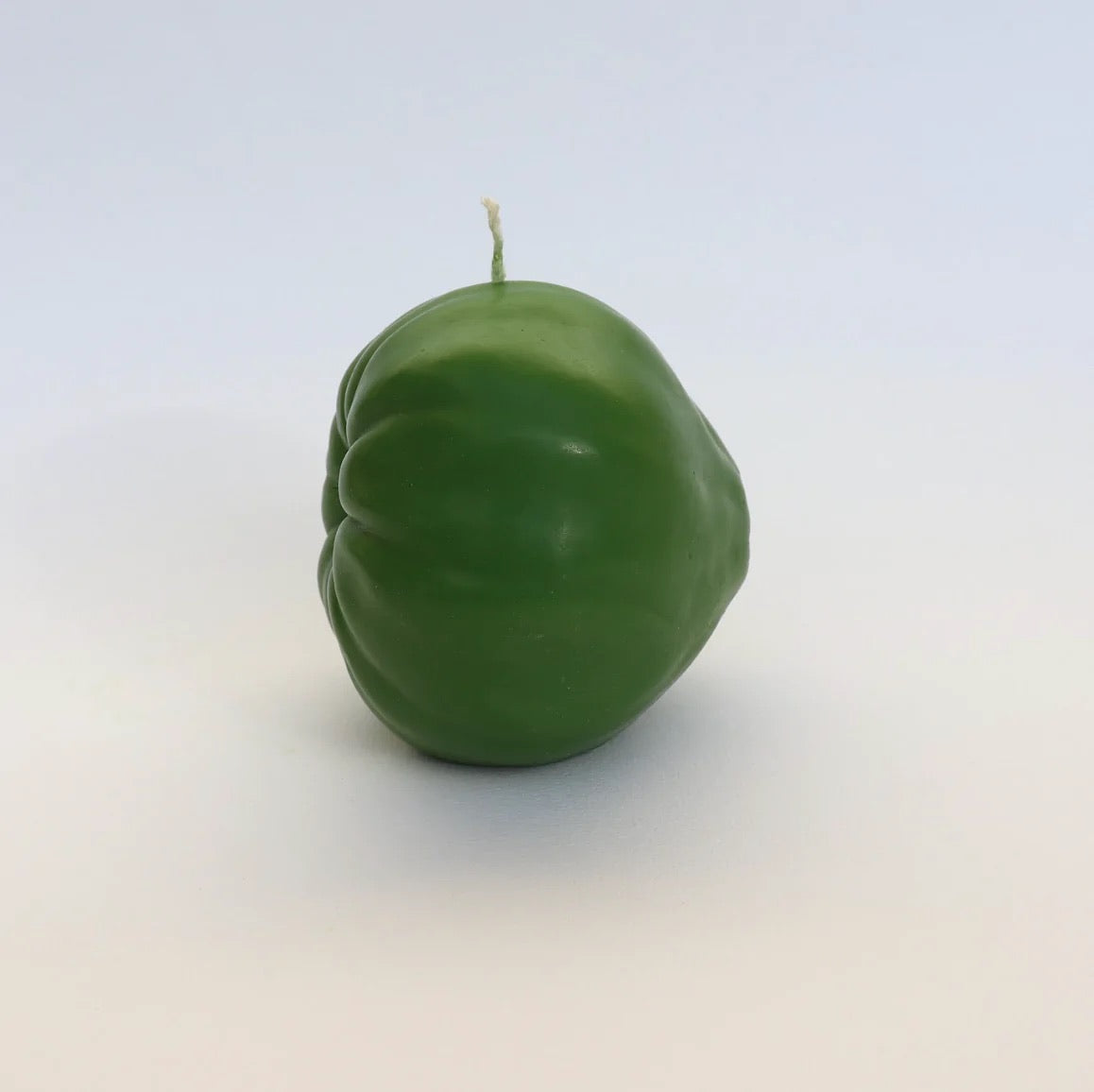 A Green Heirloom Tomato Candle – Large by Nonna&#39;s Grocer sitting on a white surface.