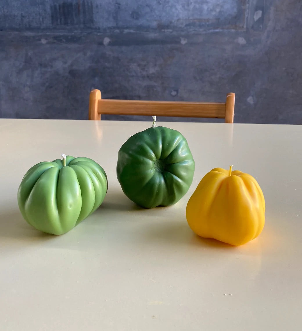 Three Green Heirloom Tomato Candles - Medium sit on a table.