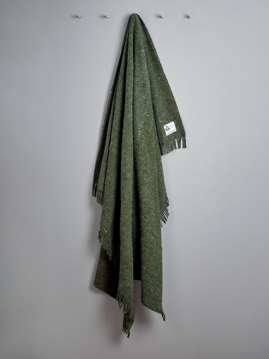 A Moss Blanket - Fringe by Seljak Brand hanging on a wall.