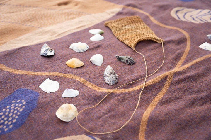 A Gather Blanket with sea shells on it, made by Seljak Brand.