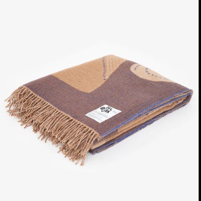 A brown and blue Gather Blanket by Seljak Brand with fringes.