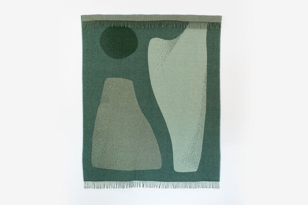 A green and white abstract design on a white background, the Pyramid Blanket by Seljak Brand.
