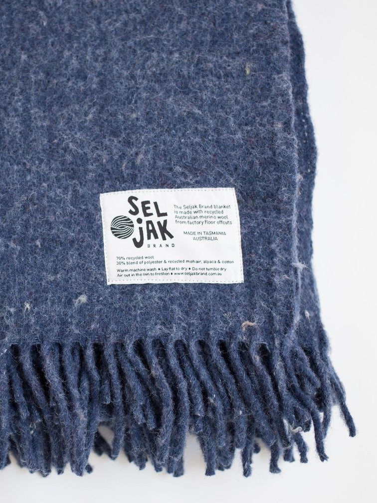 A blue Indigo Blanket – Fringe with a label that says Seljak Brand.