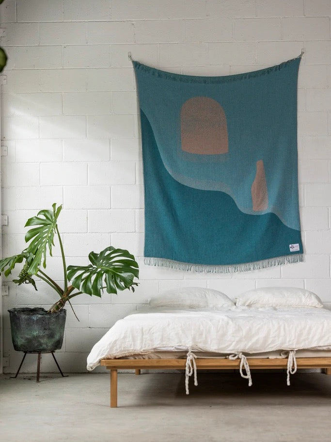 A Passage Blanket in a room with plants and a wall hanging by Seljak Brand.