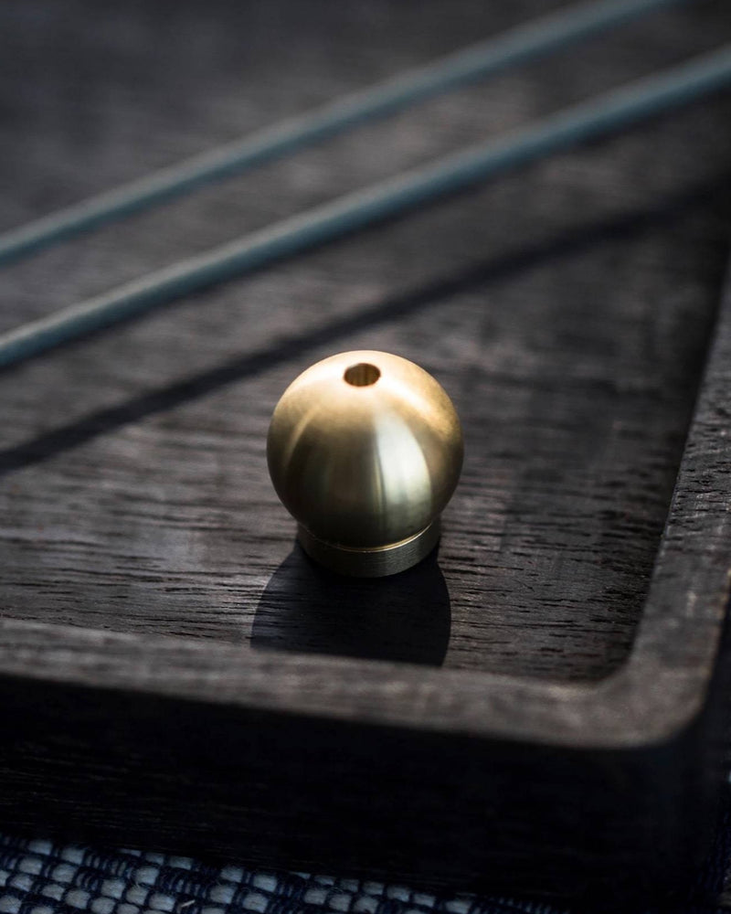 A small Senko Brass Ball Incense Holder sits on top of a black tray.