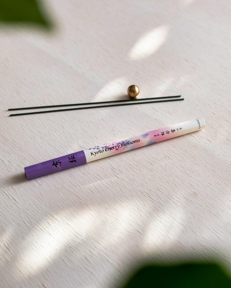 A Cherry Blossom – Kyozakura pencil with a purple flower on it next to a plant. (Brand: Senko)