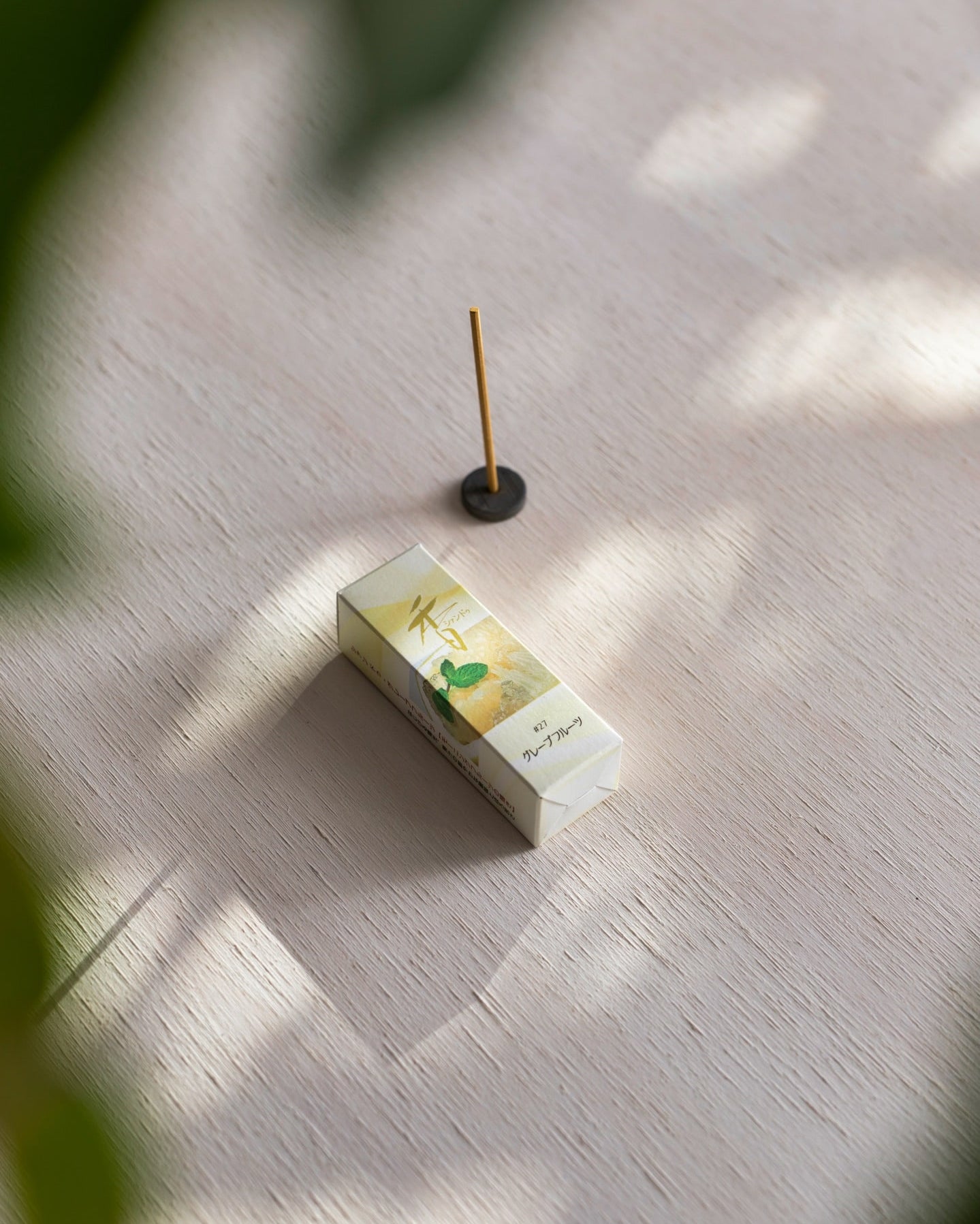 An Grapefruit with Holder – Xiang Do incense stick on top of a wooden table.