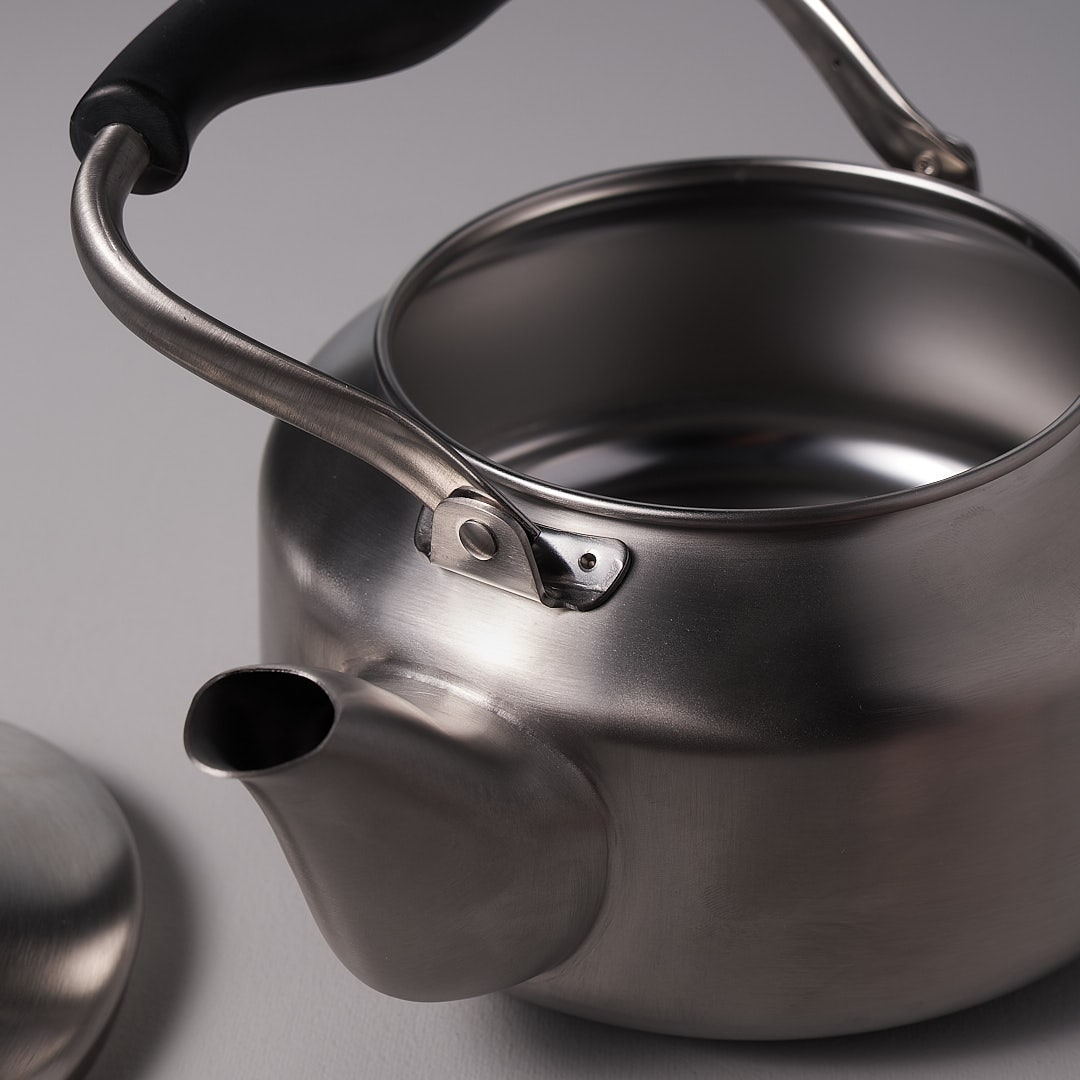A Sori Yanagi Stove-top Kettle – Brushed Steel with a lid and handle.