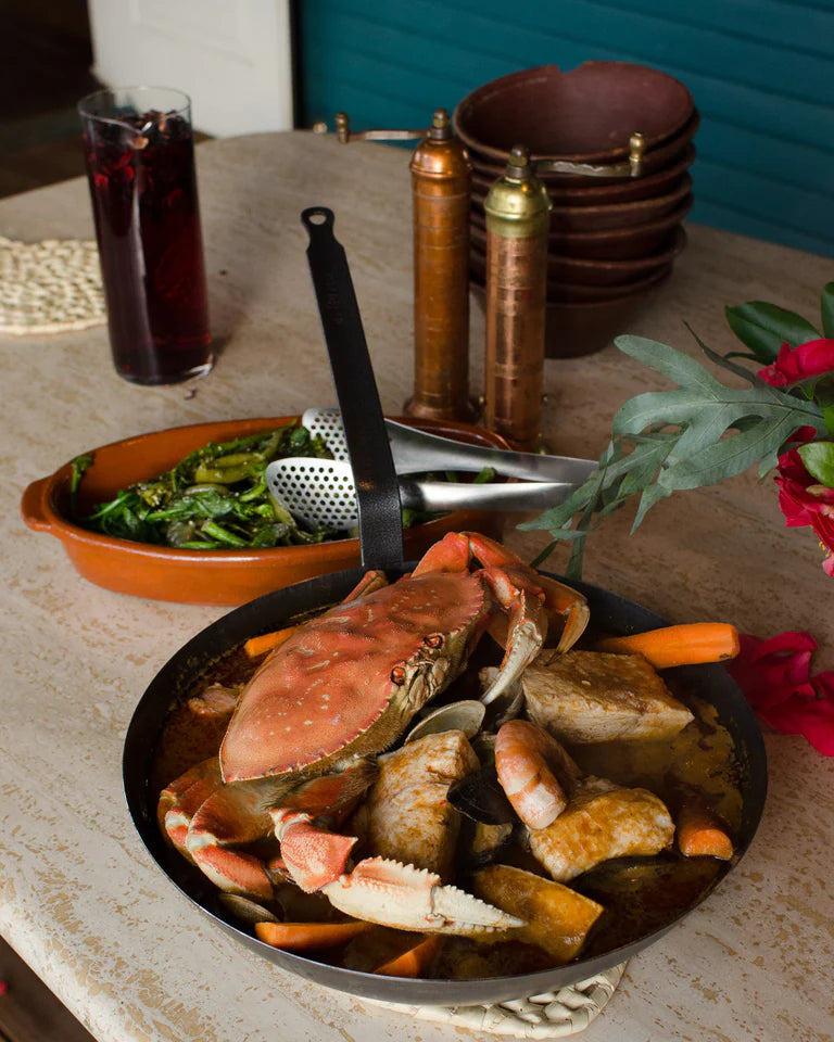 A pair of Sori Yanagi tongs full of food on a table.