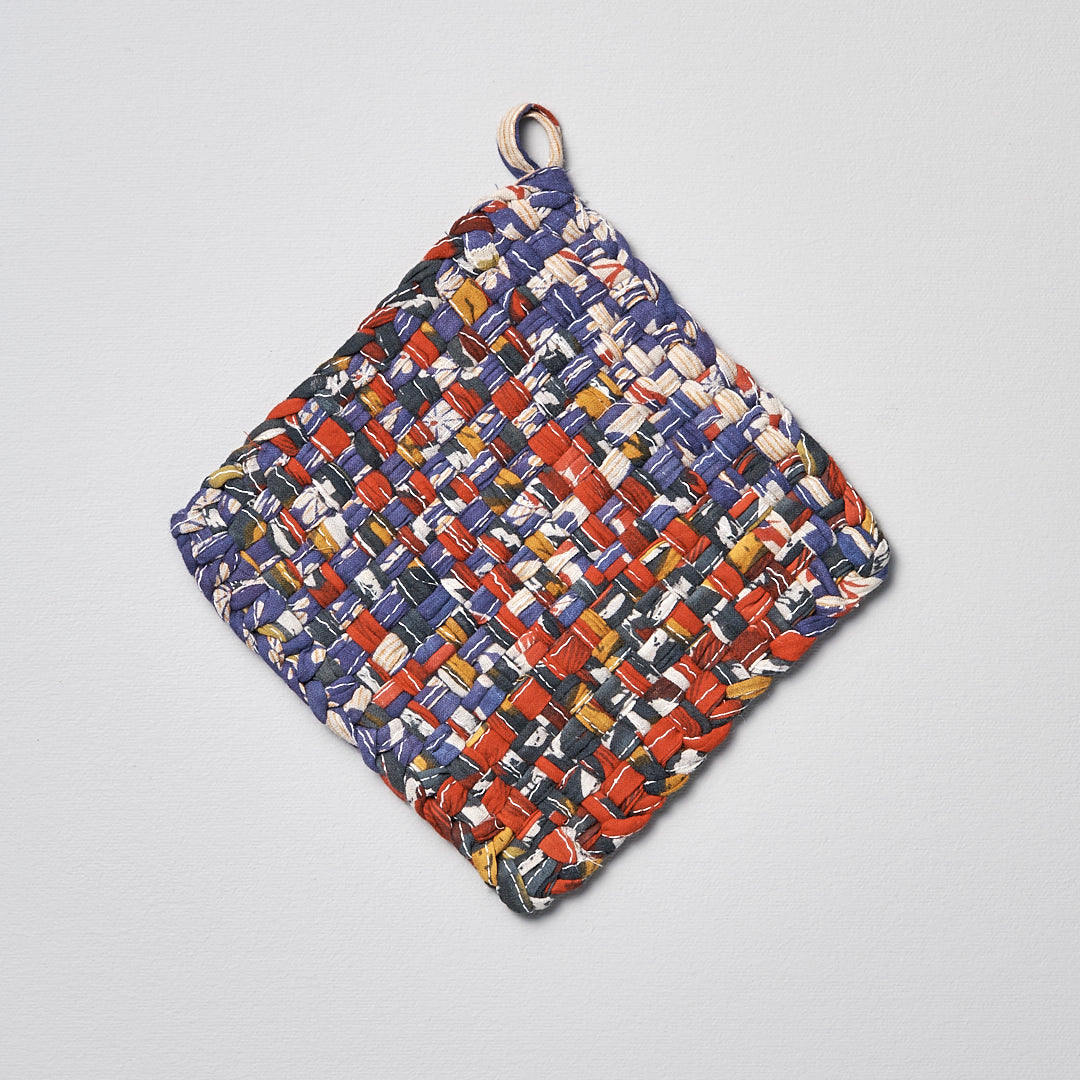 A Sari Pot &amp; Oven-tray Holder by Stitchwallah hanging on a white surface.