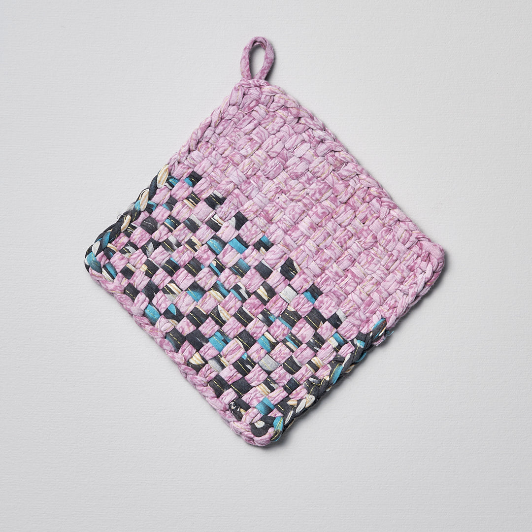 A pink and black Sari Pot &amp; Oven-tray Holder by Stitchwallah on a white surface.