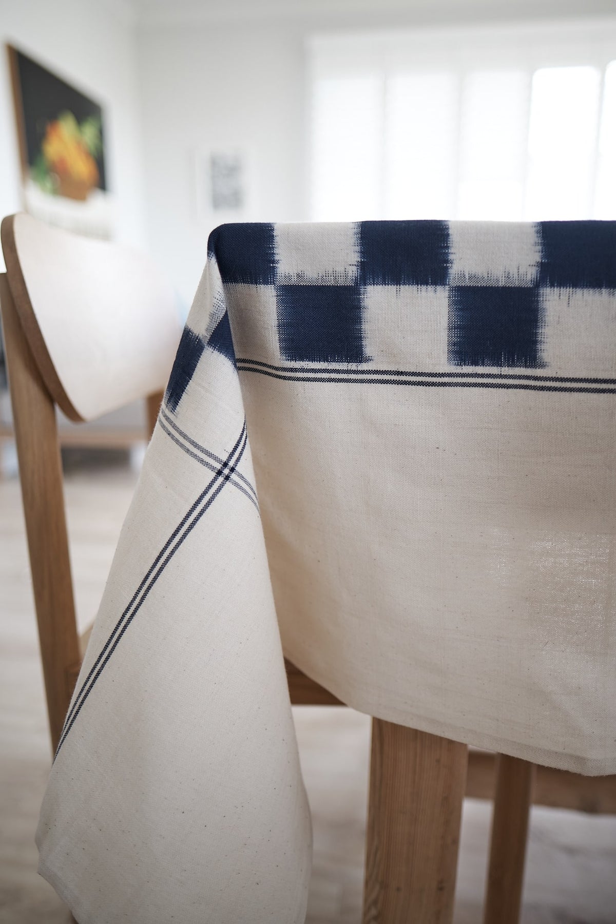 A Ikat Weave Tablecloth – Indigo Check from Stitchwallah on a wooden table.