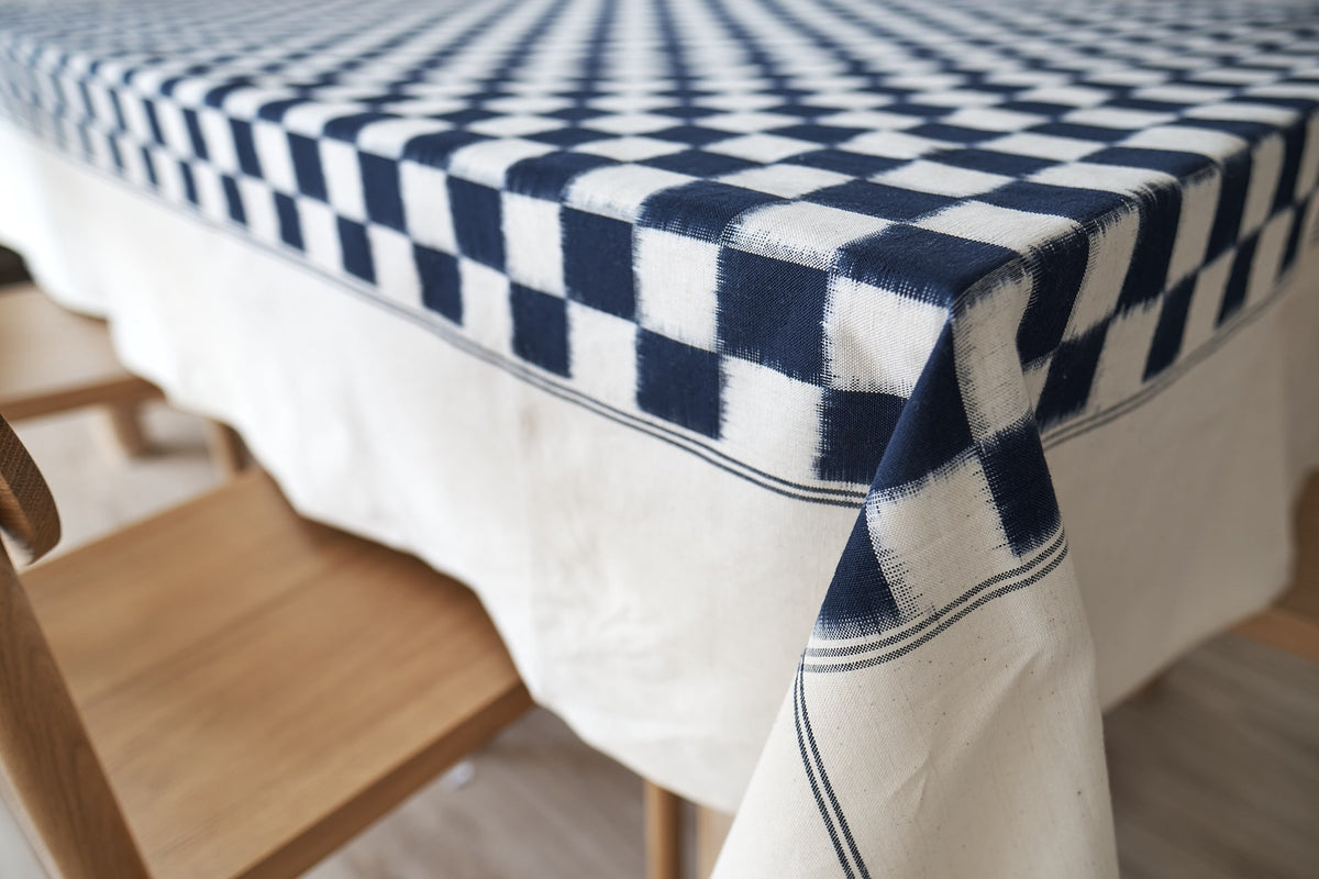 A Stitchwallah Ikat Weave Tablecloth in Indigo Check on a wooden table.