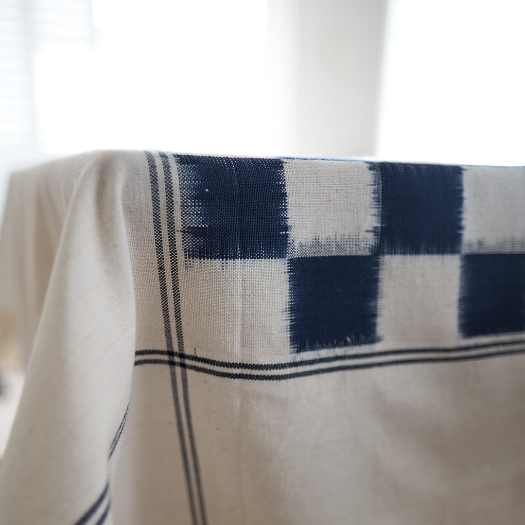 A Ikat Weave Tablecloth – Indigo Check tablecloth by Stitchwallah, in blue and white with a checkered pattern.