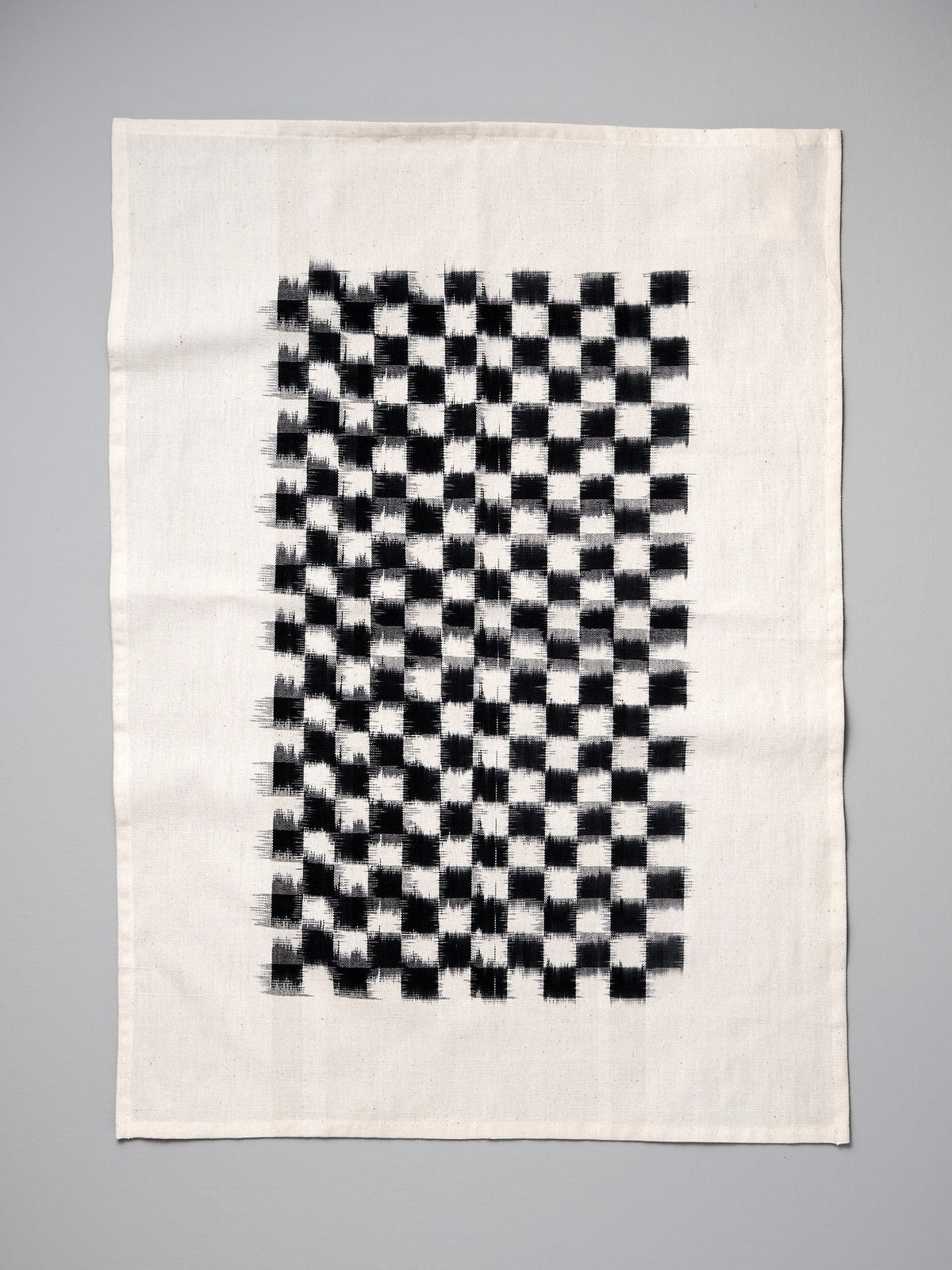 A black and white Ikat Weave Tea-towel - Black Check by Stitchwallah on a white background.