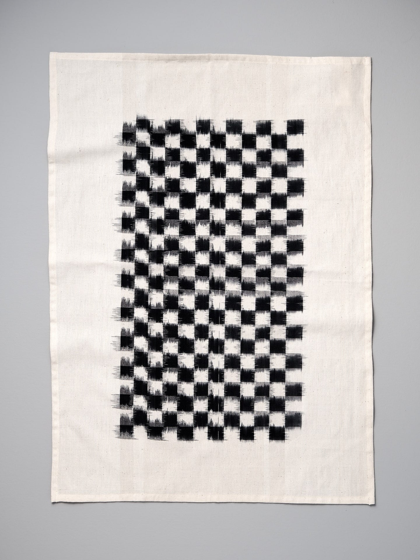 A black and white Ikat Weave Tea-towel - Black Check by Stitchwallah on a white background.