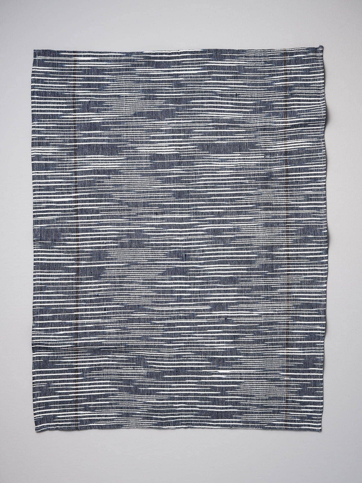 A Khadi Weave Tea-towel - Navy by Stitchwallah on a white surface.