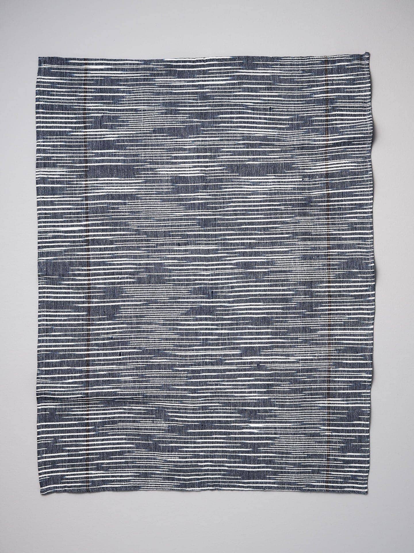 A Khadi Weave Tea-towel - Navy by Stitchwallah on a white surface.