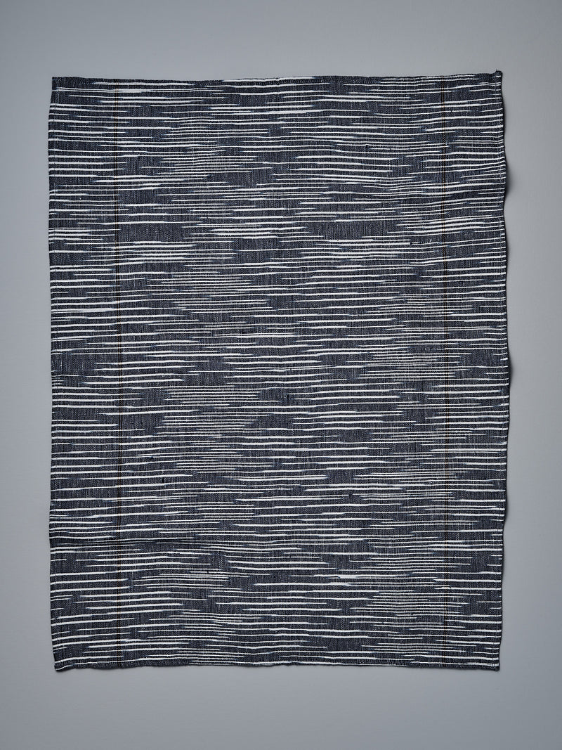 A Khadi Weave Tea-towel - Navy by Stitchwallah on a white surface.