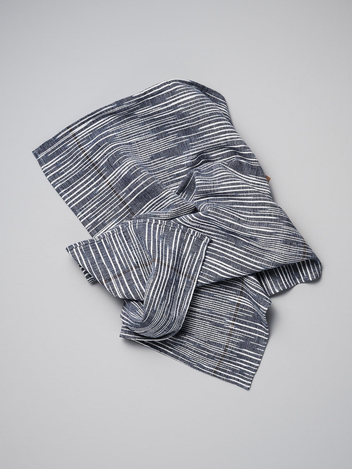 A Khadi Weave Tea-towel – Navy by Stitchwallah on a white surface.