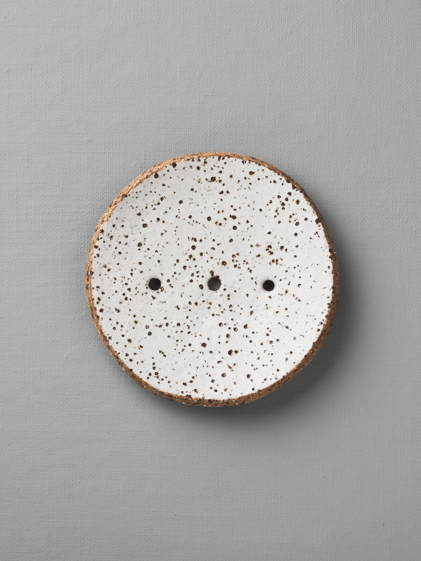 A Round Ceramic Soap Dish - White with Black Speckle from Studio Star.