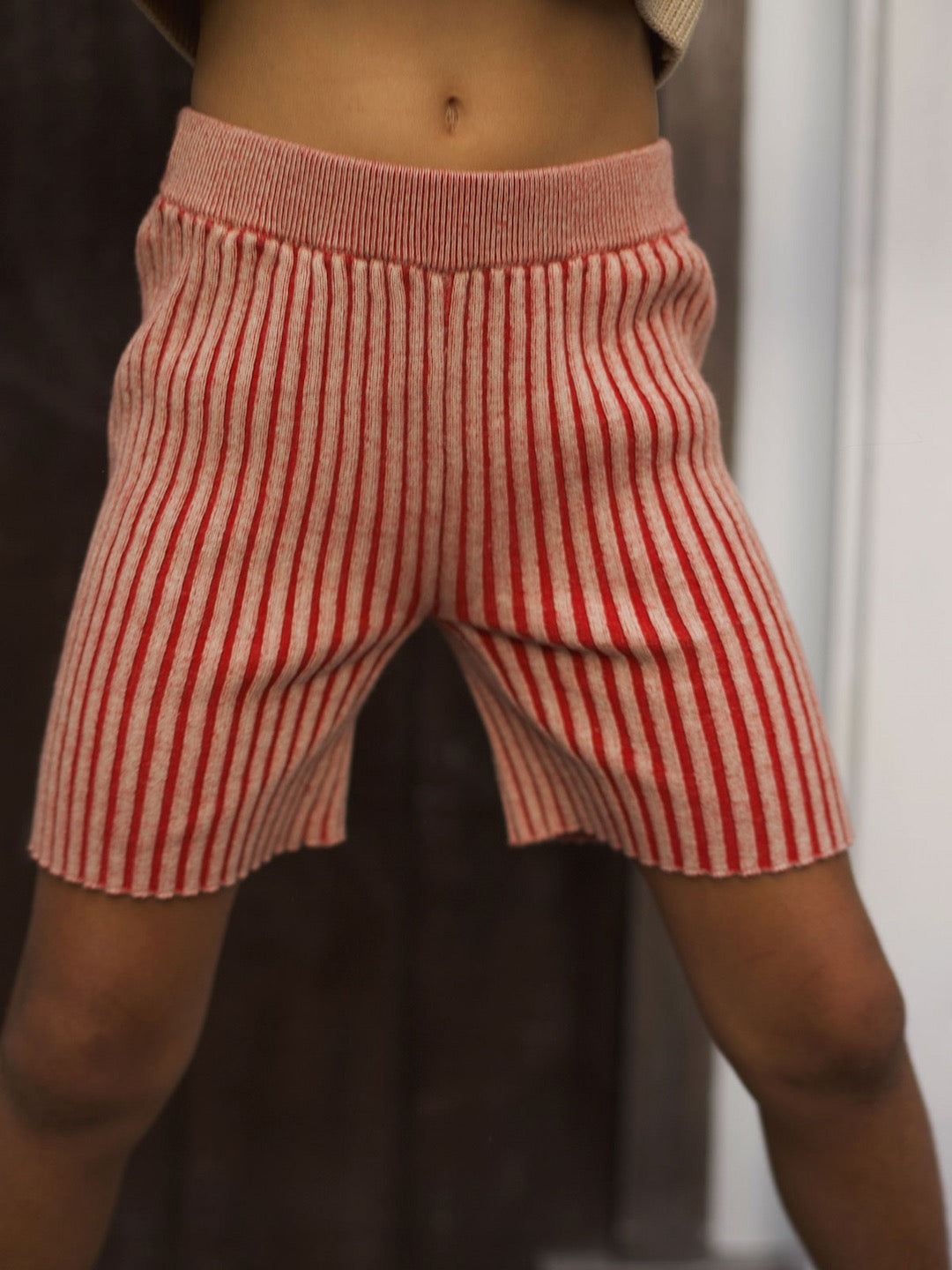 A girl wearing SUNNA STUDIOS Rue Short - Red Multi striped shorts.