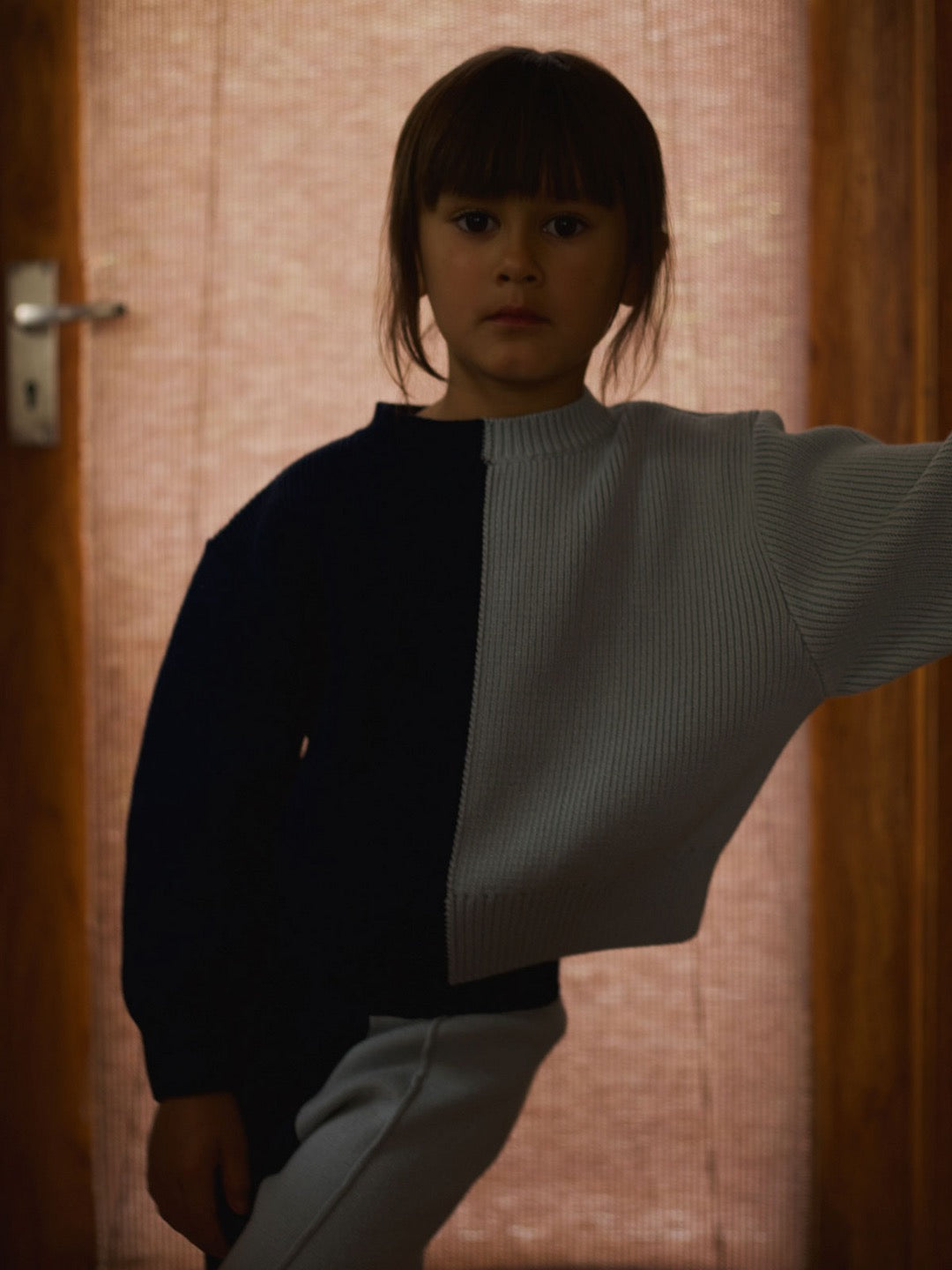 A little girl wearing a Sol Sweater – Blue Multi from SUNNA STUDIOS.