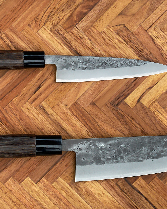 A Tadafusa Bocho Santoku Knife in a box on a white surface, suitable for all-purpose use with a focus on vegetables.